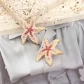 Macro detail of starfish stud earrings with pink rhinestones and white pearls - Rose Red