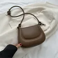 Sac à épaule en cuir matelassé marron foncé avec boucles dorées sur un blazer blanc - Marron