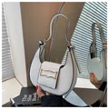 Minimalist white hobo bag with black edges and gold buckle detail shown in a mirror - White