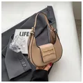 Sac croissant beige chic avec boucle dorée ondulée sur un tailleur gris élégant - Kaki