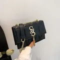 Bolso de hombro acolchado negro con cadena dorada y colgante de logotipo metálico - Negro