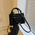 Schwarze Handtasche mit Krokodilprägung, matter Textur und goldenen Metallbeschlägen - Schwarz