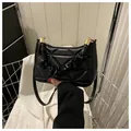 Detail der schwarzen Stepptasche mit Falten-Griff und eleganten goldenen Metallakzenten - Schwarz