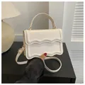 White minimalist square handbag with wave pattern flap and gold hardware accents - White