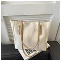 Detalle del bolso tote crema minimalista con correas marrones en contraste sobre fondo - Blanco