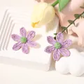 Dettaglio macro di orecchini a margherita in rafia intrecciata a mano viola e verde - Orecchini Viola