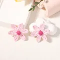 Dettaglio degli orecchini a margherita in rafia rosa fatti a mano con trama tessuta - Orecchini Rosa