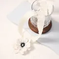 Detail of cream pleated ribbon necklace featuring a white 3D flower with dark stamens - White Flower White Ribbon / White