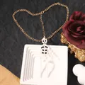 Gothic gold chain necklace with a black and white beaded skeleton pendant for Halloween - Necklace