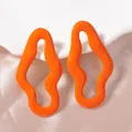 Dettaglio di orecchini ondulati arancione brillante su ceramica e seta rosa - Giallo