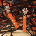 Detail of Halloween drop earrings with Trick or Treat charms on orange background - Orange