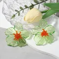 Gedetailleerd macrobeeld van groene acryl bloemoorbellen met felle oranje kralen - Groen