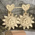 Detailed view of bohemian gold sunburst drop earrings with embossed heart design - Gold