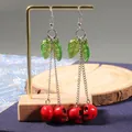 Gothic long cherry skull earrings with red resin skull drops and green leaves on silver chain - Red
