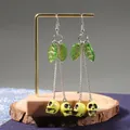 Gothic long cherry skull tassel earrings with green leaf charms on a metal stand - Yellow