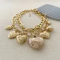 Détail du collier double chaîne dorée avec pendentifs cœurs vintage embossés sur fond texturé - Or