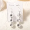 Silver disco ball tassel drop earrings with three geometric beads on display card - Silver