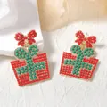 Detalle macro de pendientes de regalo de Navidad con lazo rojo y cuentas verdes - Cuentas de Arroz Rojas