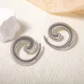 Dettaglio degli orecchini a spirale argentati con finitura metallica lucida - Argento