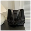 Detalle de bolso tote de lona negra con asas de cuero en un ambiente interior acogedor y cálido - Negro