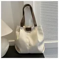 Vista de detalle del bolso tote de lona crema con asas y ribetes en contraste marrón oscuro - Blanco