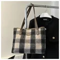Gros plan détaillé du sac cabas à carreaux avec bandoulière en cuir et logo en métal - Noir