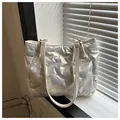 Detail of white quilted puffer tote bag with glossy finish and gold metal ring hardware - White