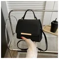 Detail der schwarzen Tasche mit Lychee-Leder-Narbung und eleganter goldener Metallschiene - Schwarz