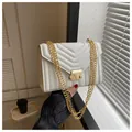 Elegant white quilted crossbody bag with gold chain strap held in a chic cafe setting - White