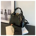 Borsa a conchiglia in vernice nera lucida con texture trapuntata e dettagli dorati - Nero