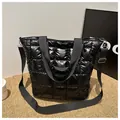 Detail of black quilted tote bag showing shiny nylon texture and wide strap - Black