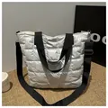 Detailed macro view of quilted puffer tote bag with silver sheen and black strap - Silver