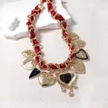 Detail of red ribbon woven chain necklace with multiple ornate gold heart charms - Red Satin Ribbon Heart Style