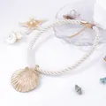 Detail of a golden scallop shell pendant on a cream braided rope beach necklace - White Rope
