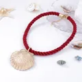Detail of red braided rope necklace featuring a large golden seashell pendant and metallic chain - Red Rope