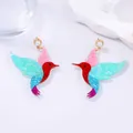 Macro detail of hummingbird earrings with multi-color glitter sequins and pearl accents - Hummingbird