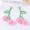 Detailed view of pink cherry fruit earrings with green beaded stems and golden studs - Pink