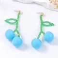 Beaded cherry earrings with light blue fruit and green leaf pendant on white background - Blue