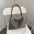 Elegant tweed handbag with chain handle and Fashion label on white chair display - Black