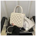 Elegante cremeweiße Stepptasche mit Tragegriff auf einem schwarzen Stuhl - Weiß