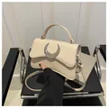 Sac bandoulière chic de couleur crème avec grande boucle de lune argentée sur chaise - Kaki