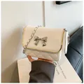 Detail of white quilted crossbody bag with silver bow accent and gold edge trim - White