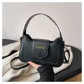 Detail of black faux leather crossbody bag with gold FASHION text and wide handle - Black