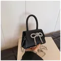 Detail van zwarte mini-tas met sprankelende strass-strik en een litchi-leer textuur look - Zwart