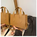 Camel leather tote bag with top handles and adjustable shoulder strap shown in a mirror - Dark Brown