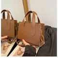 Chic brown top-handle square bag with adjustable shoulder strap and gold hardware detail - Caramel color