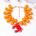 Dettaglio della collana di perle arancioni a goccia con ciondolo a forma di granchio rosso - Arancione