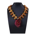 Détail du collier de perles ambrées avec grand pendentif conque rouge sur buste noir - Ambre