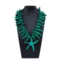 Detailopname van de turquoise zeester hanger en imitatie koraal takken ketting - Donkergroen