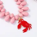 Dettaglio collana di perle rosa con ciondolo a forma di granchio rosso e finiture oro - Rosa